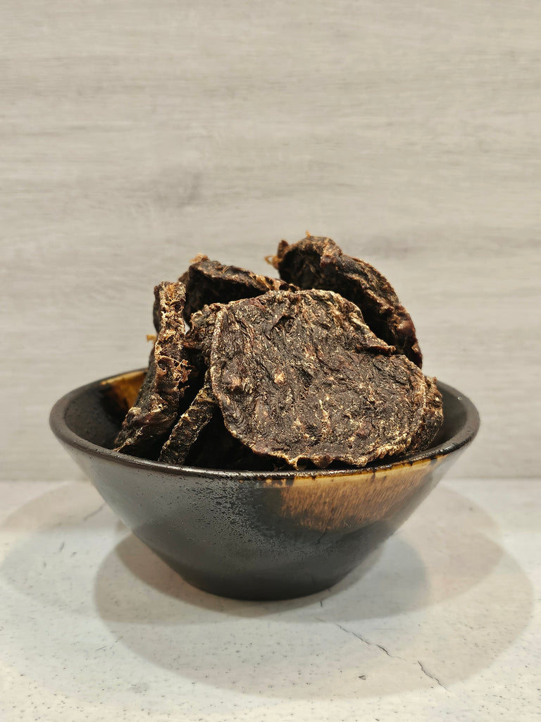Dehydrated roo and rabbit patties for dogs in a brown bowl on a light gray background