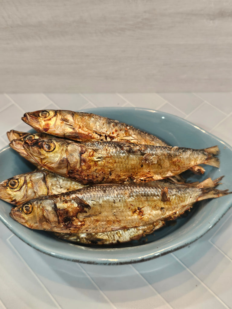 close up of several dried whole sardines - suitable for both dog and cat treats in a blue dish on a decorated background