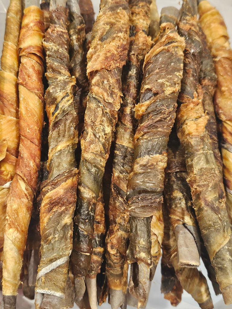 A pile of dried fish and shark roll treats for dogs in a clear plastic container